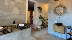 A modern bathroom with a large mirror, a round sunburst mirror, a wooden console, and a stone-tiled floor. - SIBON Wine & Spa Resort Jeruzalem (Ljutomer)