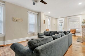 A living room with a sectional sofa, a ceiling fan, and a fireplace.
