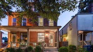 A two-story house with a covered porch, a brick facade, and a small front yard.
