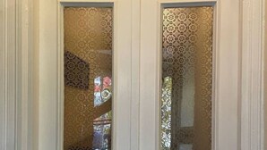Puerta doble blanca con paneles de vidrio decorativos y cerradura con llave.