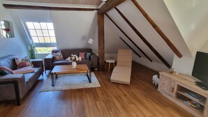 Een woonkamer in loftstijl met een houten vloer, een bank, een salontafel, een tv-meubel en een raam met uitzicht.