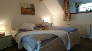 A bedroom with a bed, bedside table, lamp, and a painting on the wall. - 2 combined vacation apartments for up to 7 people - separate use possible! (Ihlow)