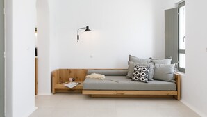 A minimalist room with a wooden bench bed, a wall-mounted lamp, and a window with a view. - Alio Suites-Suite N2 with private swimming pool (Νάξος)