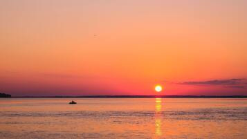 A sunset over a calm body of water with a boat in the distance.