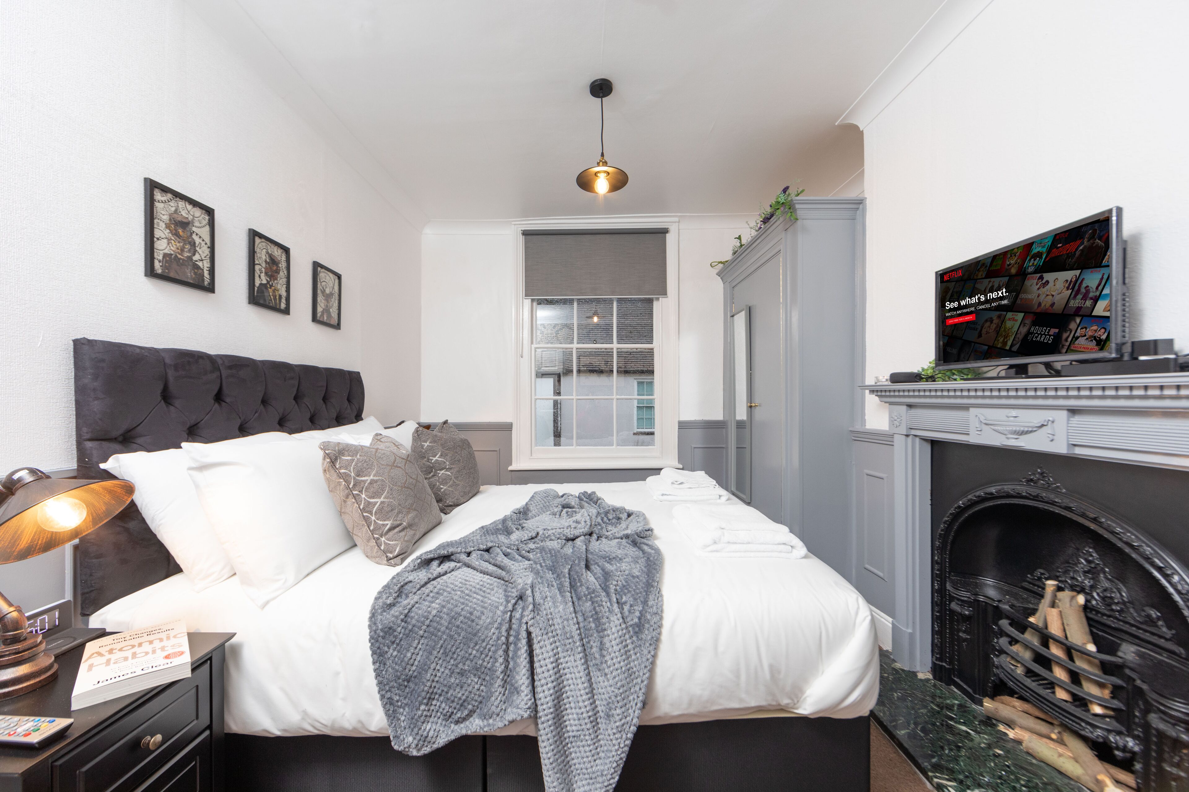 Une chambre à coucher avec un lit, une lampe de chevet et un téléviseur diffusant du contenu Netflix.