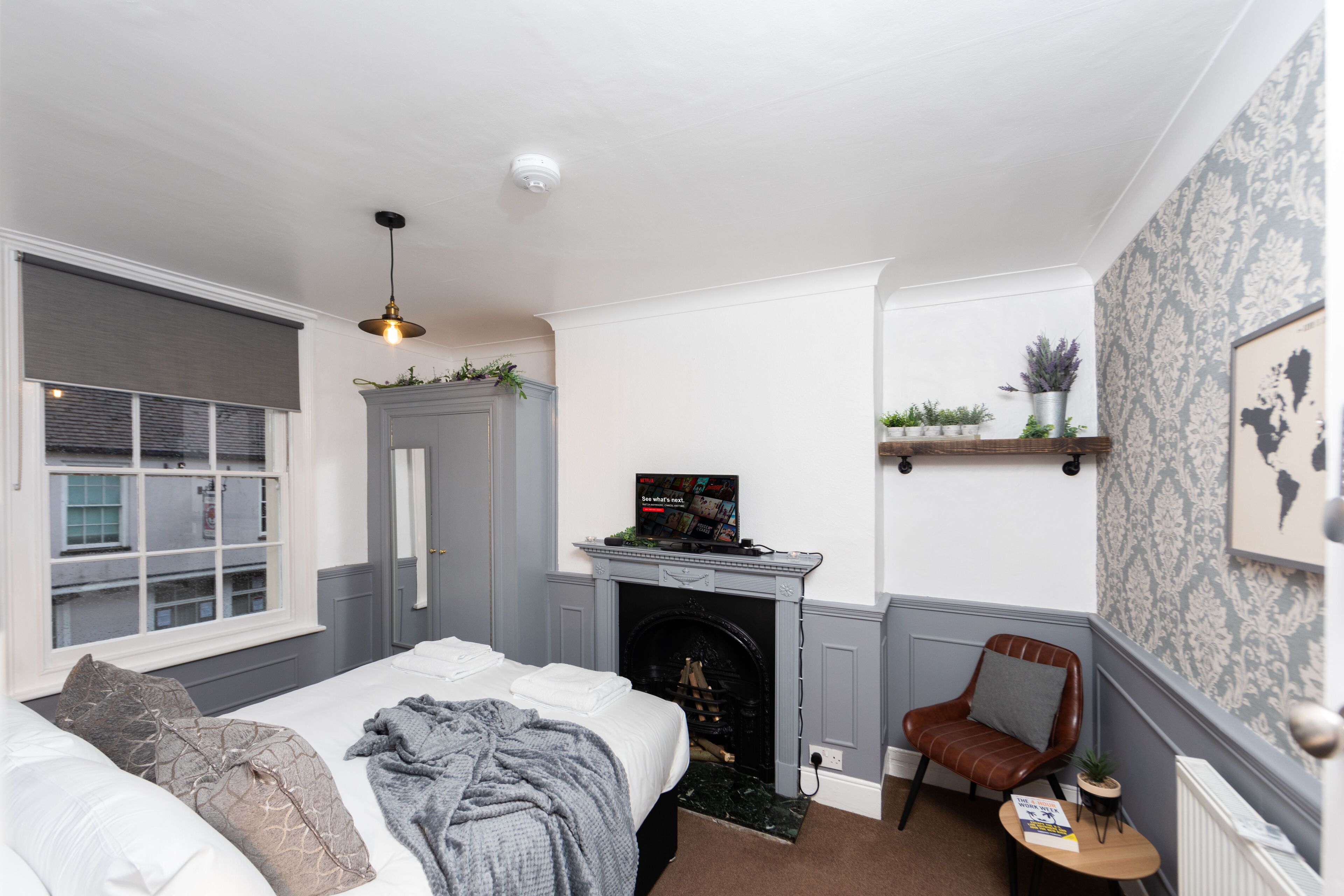Een slaapkamer met een bed, een open haard, een televisie en een stoel.
