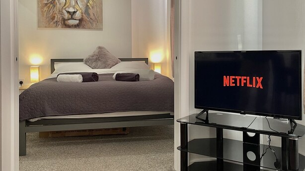 Une chambre à coucher avec un lit, un tableau, une télévision et une moquette.