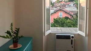 Ein Zimmer mit einem Eckfenster, einem türkisblauen Kommode und einer weißen Klimaanlage.