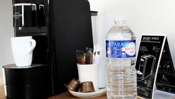 Eine Kaffeemaschine, eine Wasserflasche, eine Tasse und ein Kaffee-Pod-Halter auf einer Tischplatte.