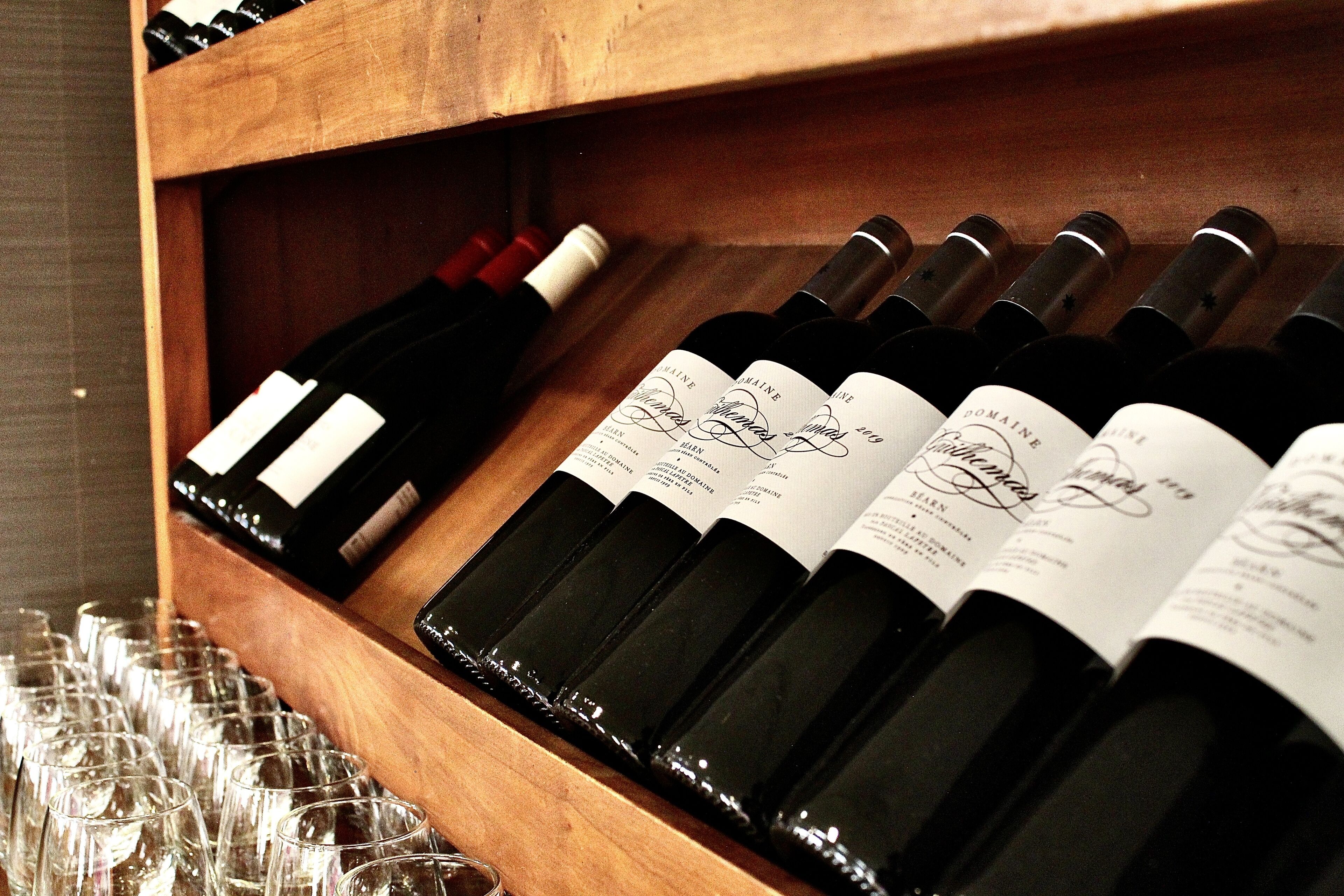 A wooden wine rack with several bottles of wine and empty wine glasses.