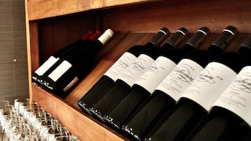 A wooden wine rack with several bottles of wine and empty wine glasses.