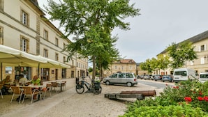 Una calle con mesas al aire libre, una bicicleta y coches aparcados.