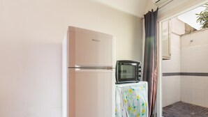 A compact kitchen with a refrigerator, a microwave, and a small table covered with a floral tablecloth. - Casa Conchiglia by BarbarHouse (Gallipoli)