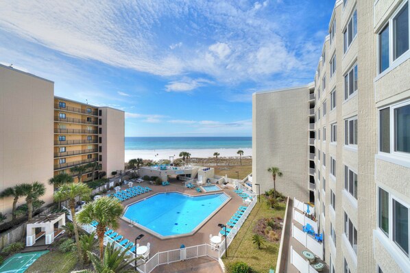 A hotel with a swimming pool, beach view, and multiple balconies.