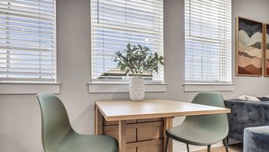A modern room with a wooden desk, two green chairs, a white vase with a plant, and a grey couch. - Cozy Secluded Studio With Full-Kitchen, Washer And Dryer - The Works! (Austin)