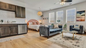 A modern living room with a sofa, a coffee table, and a bed with a headboard. - Cozy Secluded Studio With Full-Kitchen, Washer And Dryer - The Works! (Austin)