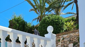 Una escalera blanca de piedra que lleva a un balcón con barandilla blanca.