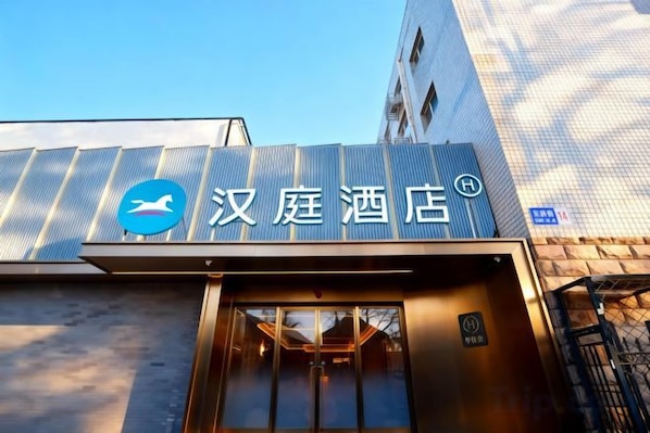 A hotel entrance with a sign displaying the hotel's name and logo.