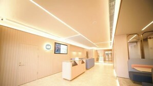 En moderne hotellobby med en receptionsdisk, et loungeområde og en trappe op til en anden etage.