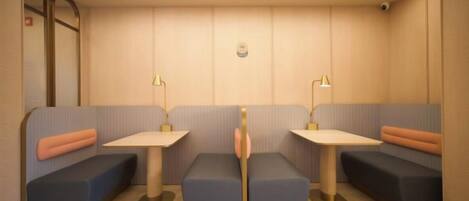 A room with two seating areas, each with a table and lamp, and a wall-mounted camera.