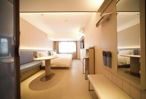 A modern hotel room with a bed, a seating area, a small table, and a mirror. - HanTing Hotel (Beijing Xidan Mall) (Beijing)
