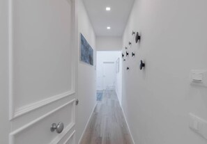Stylish hallway with a polished floor, framed artwork, and modern lighting.