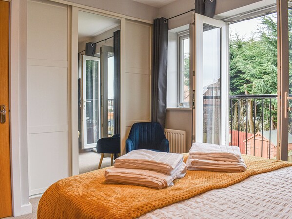 A bedroom with a bed, a chair, and a view of a balcony with a railing. - 2 bedroom accommodation in Whitby (Whitby)