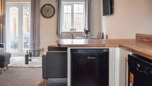 Eine kleine Küche mit Kühlschrank, Geschirrspüler und einem Essbereich mit Stühlen und Tisch.