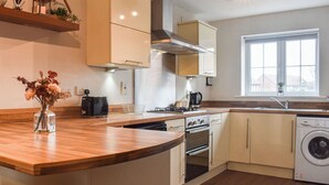 Eine moderne Küche mit Holzarbeitsplatten, einem eingebauten Backofen, einem Geschirrspüler und einem Fenster, das für natürliches Licht sorgt.