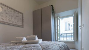 A bedroom with a bed, a large window, and a view of the outside.