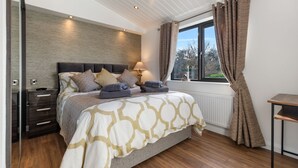 Una camera da letto con un letto, comodini, una finestra con tende e vista su del verde all'esterno.