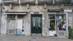 Fachada de un edificio con una puerta verde, un letrero que dice 'Francisco Sá atelier de cabelos' y un escaparate con maniquíes.