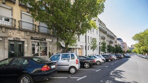 Una calle bordeada de coches aparcados y edificios, incluyendo un escaparate con un cartel que dice "Francisco Sá atelier de cheveux".