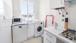 A modern kitchen with a washing machine, microwave, sink, and gas stove.