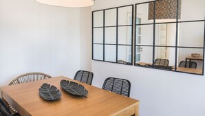 Un comedor con una mesa de madera, sillas negras y un espejo grande con un diseño geométrico.