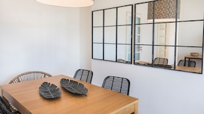 A dining area with a wooden table, black chairs, and a large mirror with a geometric pattern.