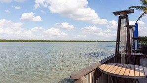 A wooden deck with a table and chairs overlooking a body of water.