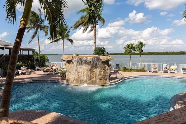 Relax by the serene pool surrounded by palm trees and lounge chairs.