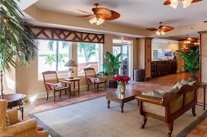 Relax in the traditional lobby with a reception desk, sofa, and chairs, surrounded by large windows and palm trees.