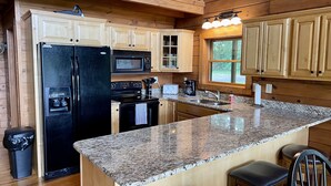 A kitchen with granite countertops, a refrigerator, stove, microwave, and a window. - Beautiful secluded cabin - sleeps 12, fire pit, fishing pond, grill, game room (russell springs)