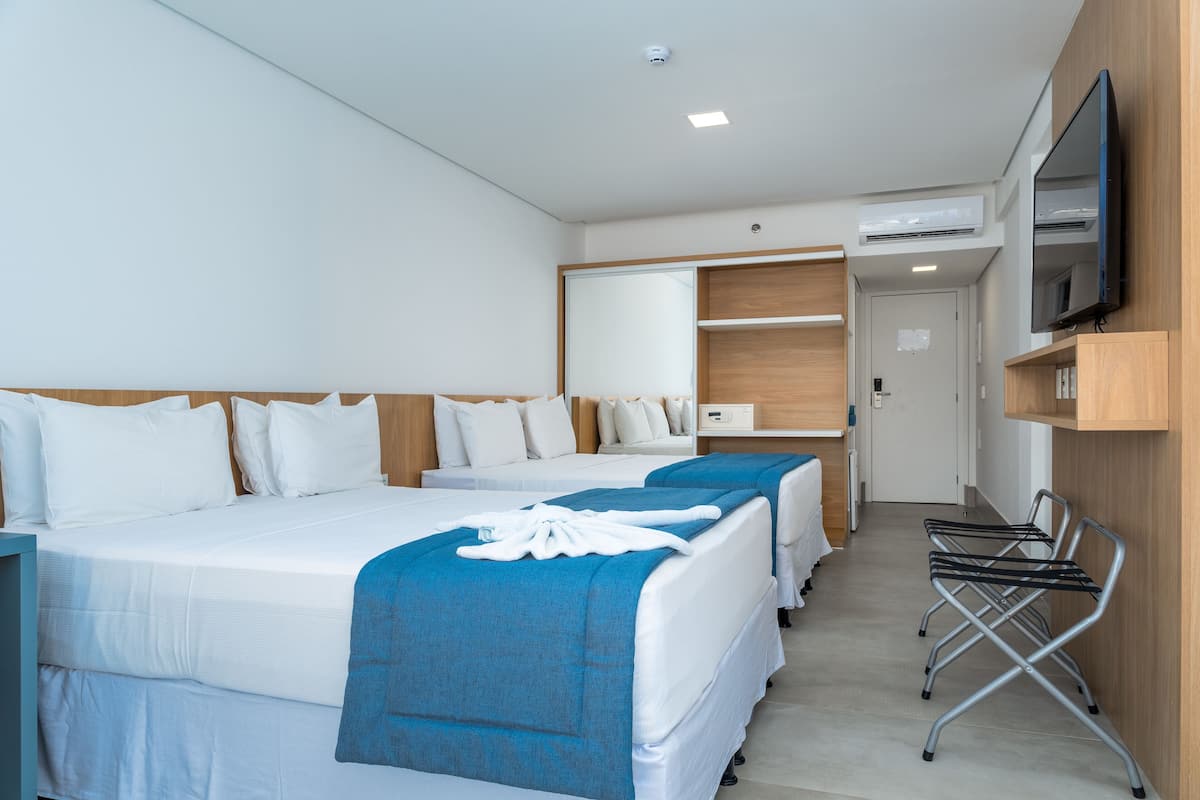 Een hotelkamer met twee bedden, een televisie, een bureau en een spiegel.