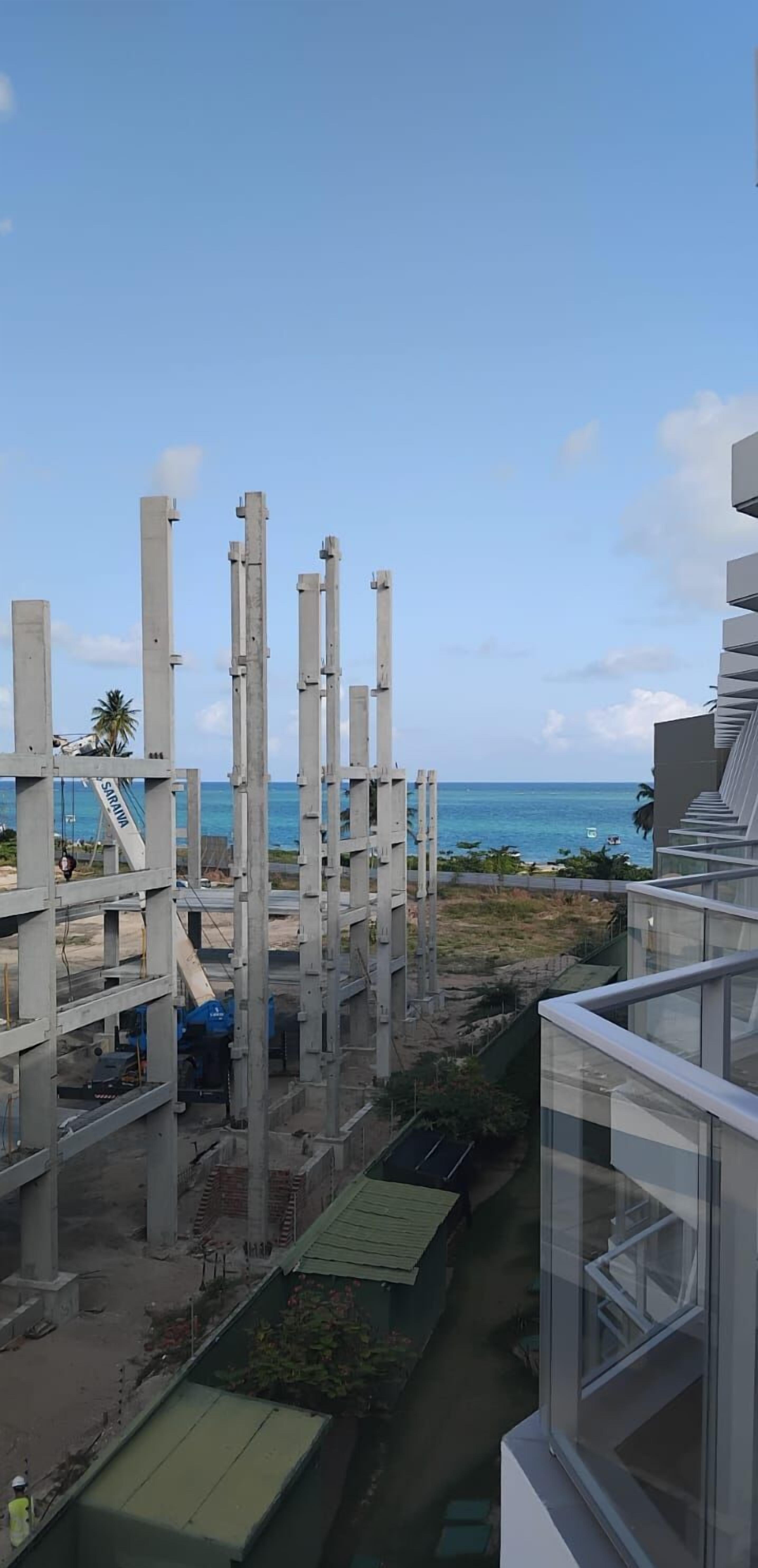 Una obra en construcción con columnas de hormigón visto y vista al océano.