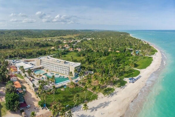 Vista aérea de un resort con un edificio grande, una playa y un área de piscina.