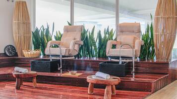 Relax in a serene spa area with comfortable lounge chairs, a stool, and a bench, surrounded by lush greenery.