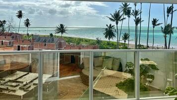 Uma varanda com vista para a praia e palmeiras.