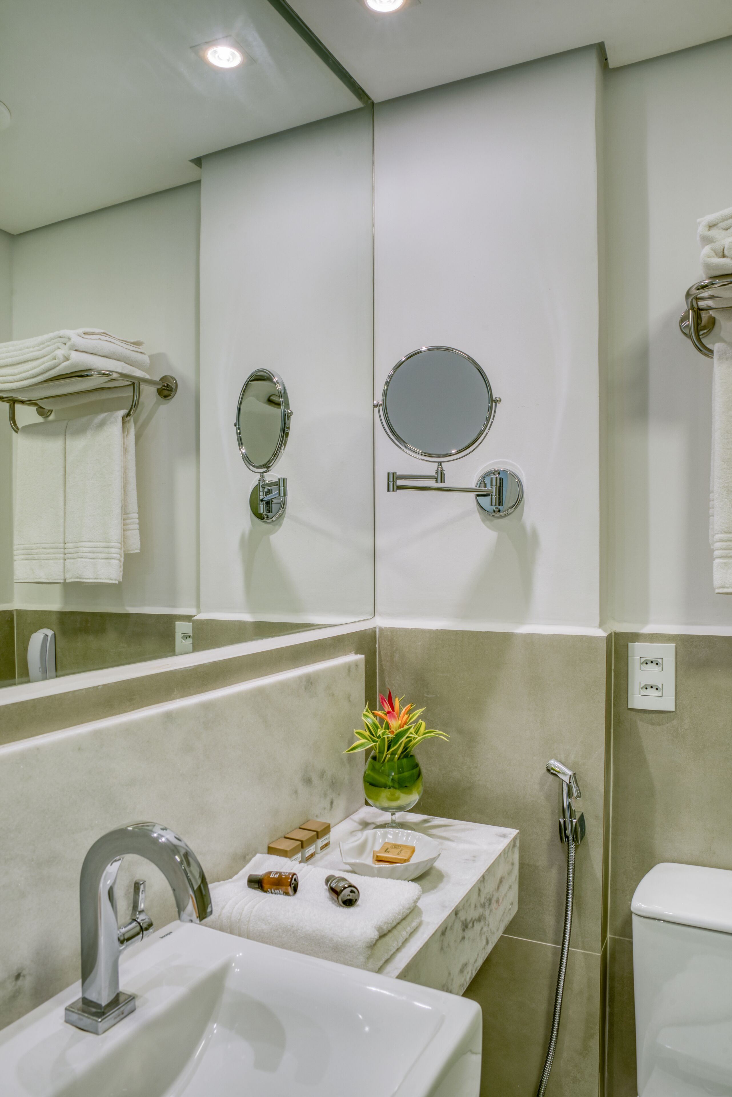 A bathroom with a sink, mirror, towel rack, and shower.