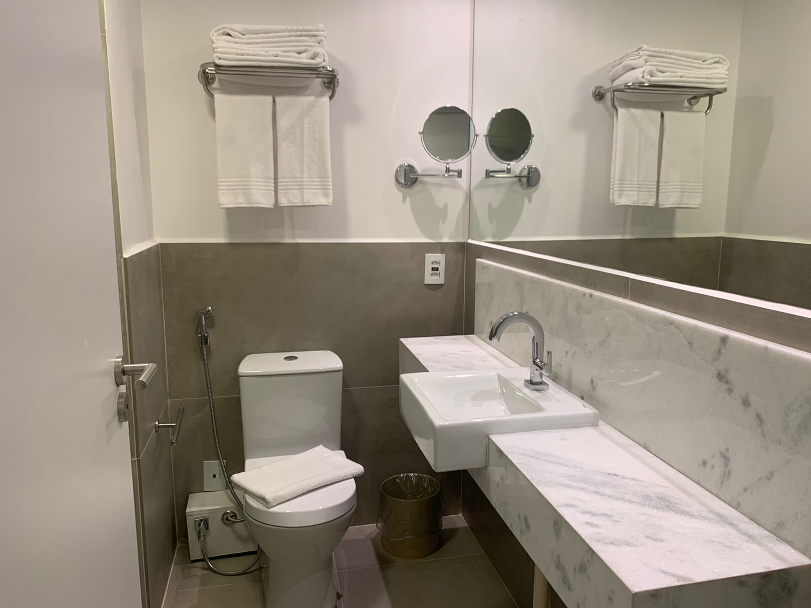 A modern bathroom with a toilet, bidet, and a large mirror.