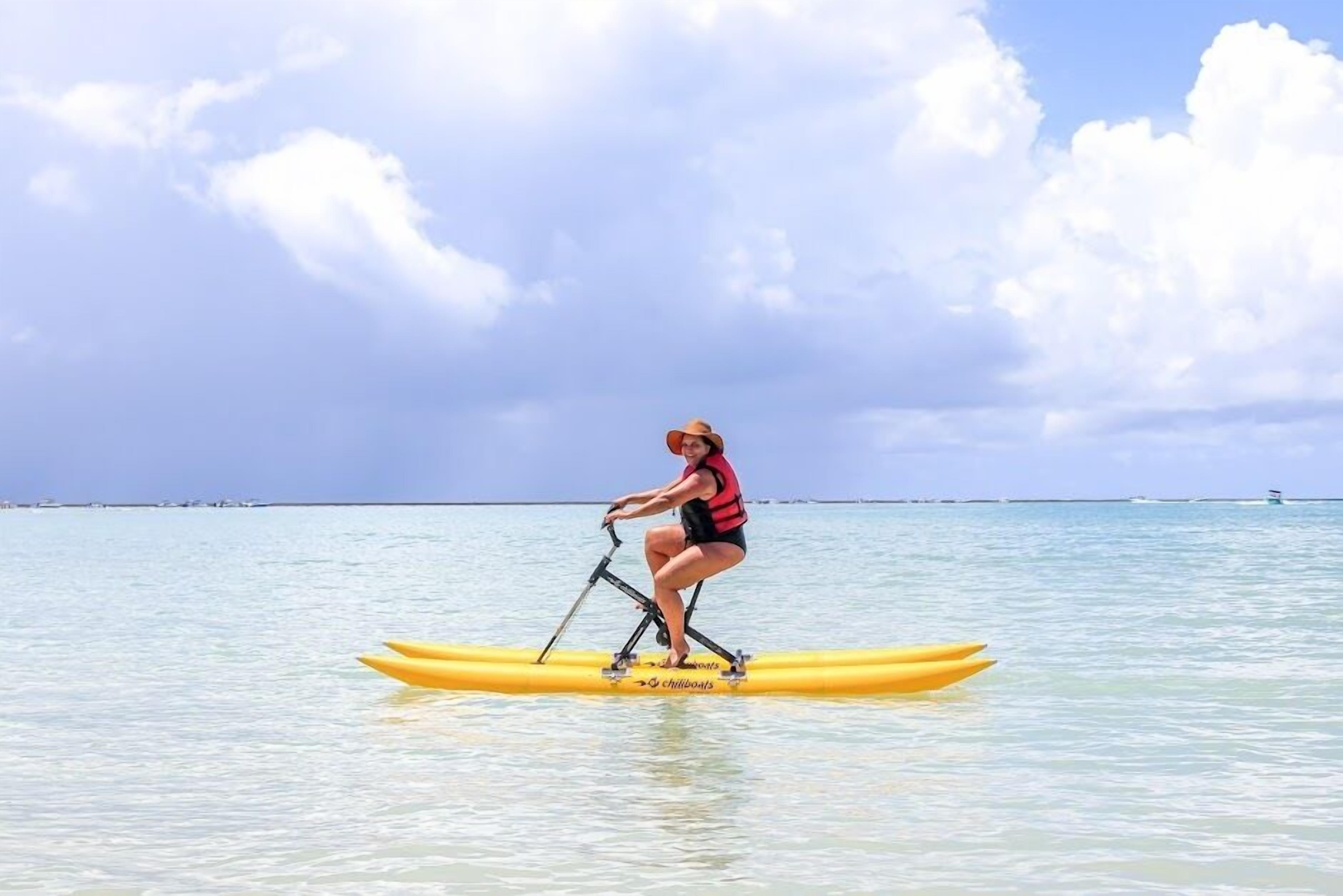 A person on a yellow paddleboard in calm waters with a clear sky.