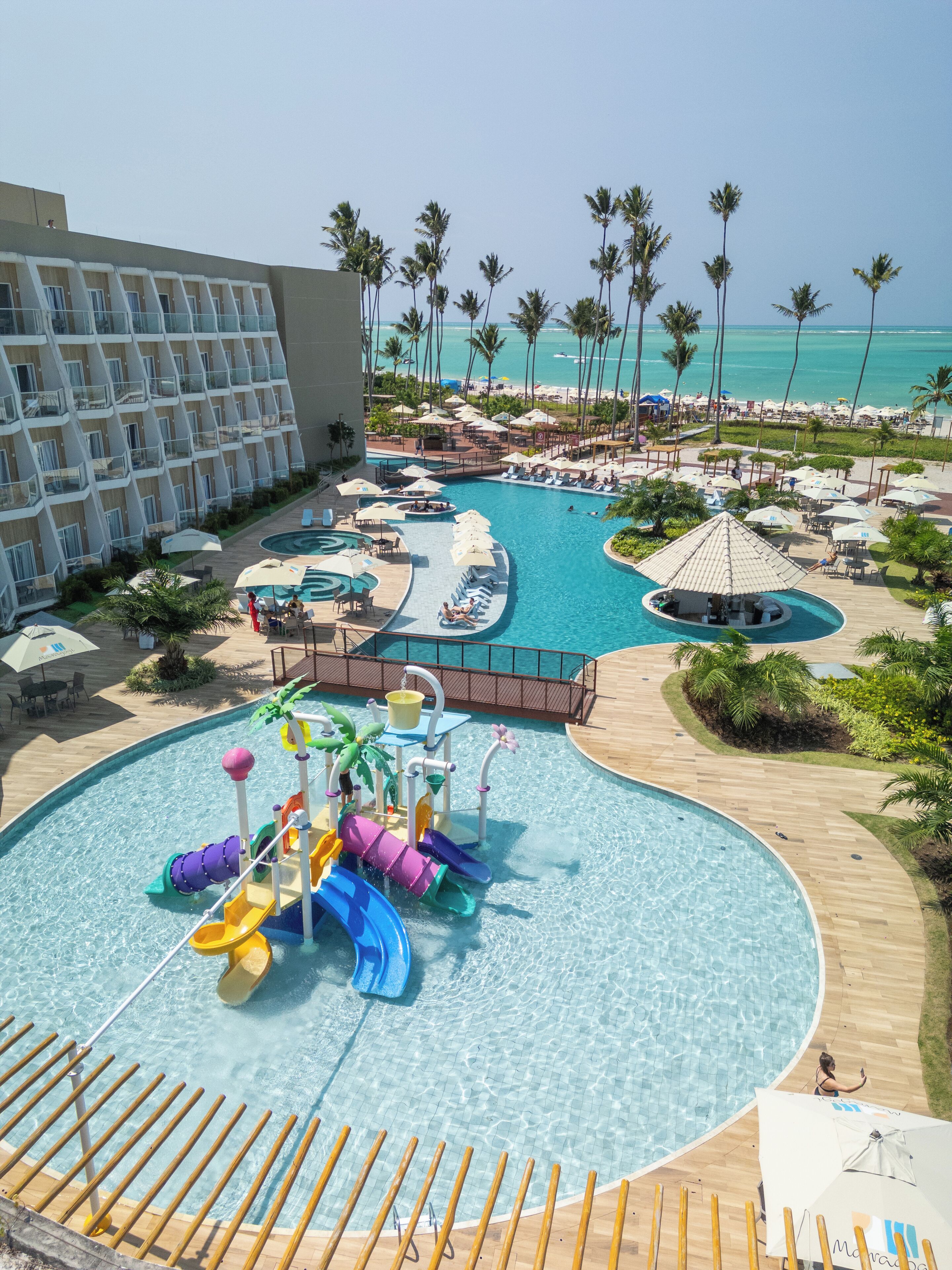 Un resort con una amplia zona de piscina, que incluye un tobogán de agua y varias áreas de descanso.