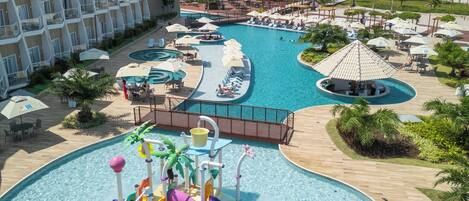 A resort with a large pool area, including a water slide and multiple lounge areas.